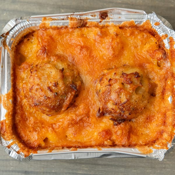 A close-up of a baked dish with a golden-brown, cheesy crust in a foil container.